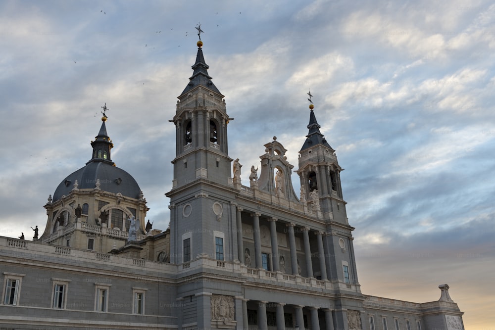 Neo-gothic facade and dome of Santa María la Real de La Almudena, Madrid's Catholic cathedral, against a dramatic sky on a winter afternoon.