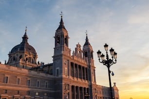 Vista lateral de Santa María la Real de La Almudena, la catedral católica de Madrid, iluminada por los colores cálidos al atardecer.