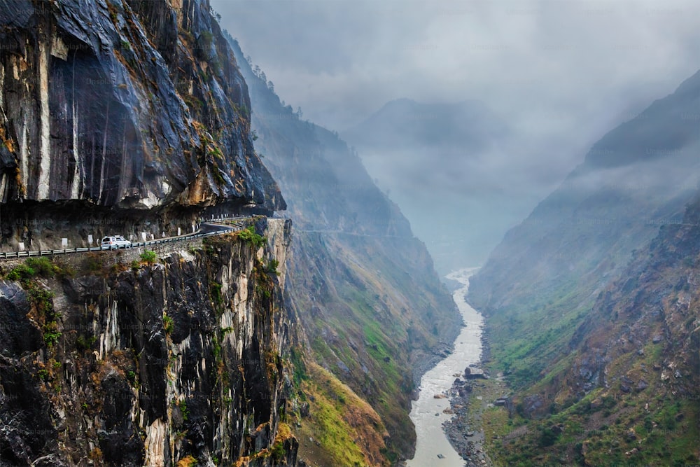 絶壁の上の峡谷のヒマラヤ山脈の危険な道路上の車