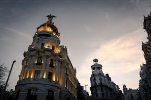 Nachtansicht der Straßen Alcalá und Gran Via in Madrid. Mehrere Wahrzeichen wie das Metropolis Building oder das Telefónica Building sind zu erkennen.