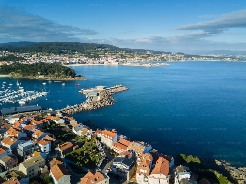 Rocas, barcos y pequeño faro en el puerto de Portnovo, Galicia, España.