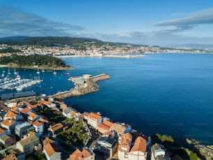 Rocas, barcos y pequeño faro en el puerto de Portnovo, Galicia, España.