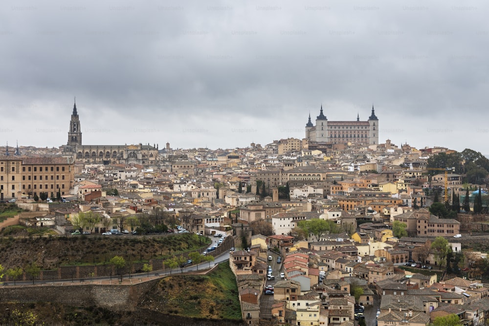 Panoramablick auf Toledo und den Tejo an einem regnerischen Frühlingstag, mit der Kathedrale und dem Alcázar, die sich über die Skyline erheben.