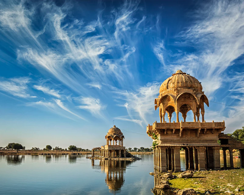 Gadi Sagar lake in Jaisalmer full of water under a streaked monsoon sky