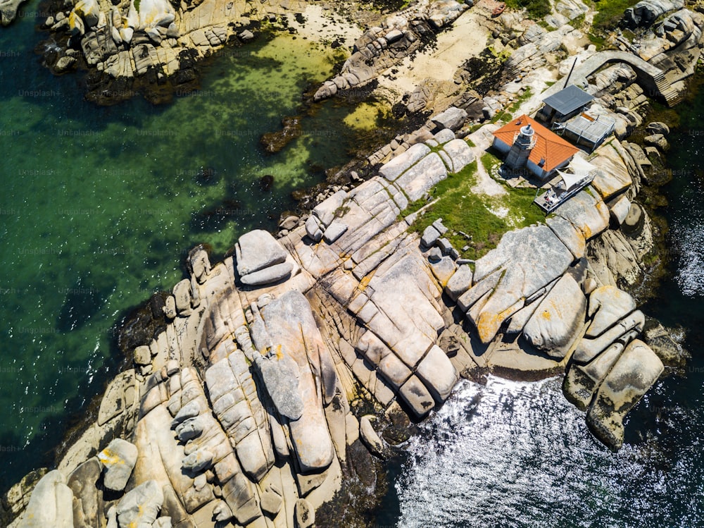 スペインのガリシアにある小さな島にある岩、ボート、小さな灯台。