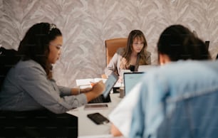 テーブルの周りに座ってノートパソコンで作業する女性のグループ