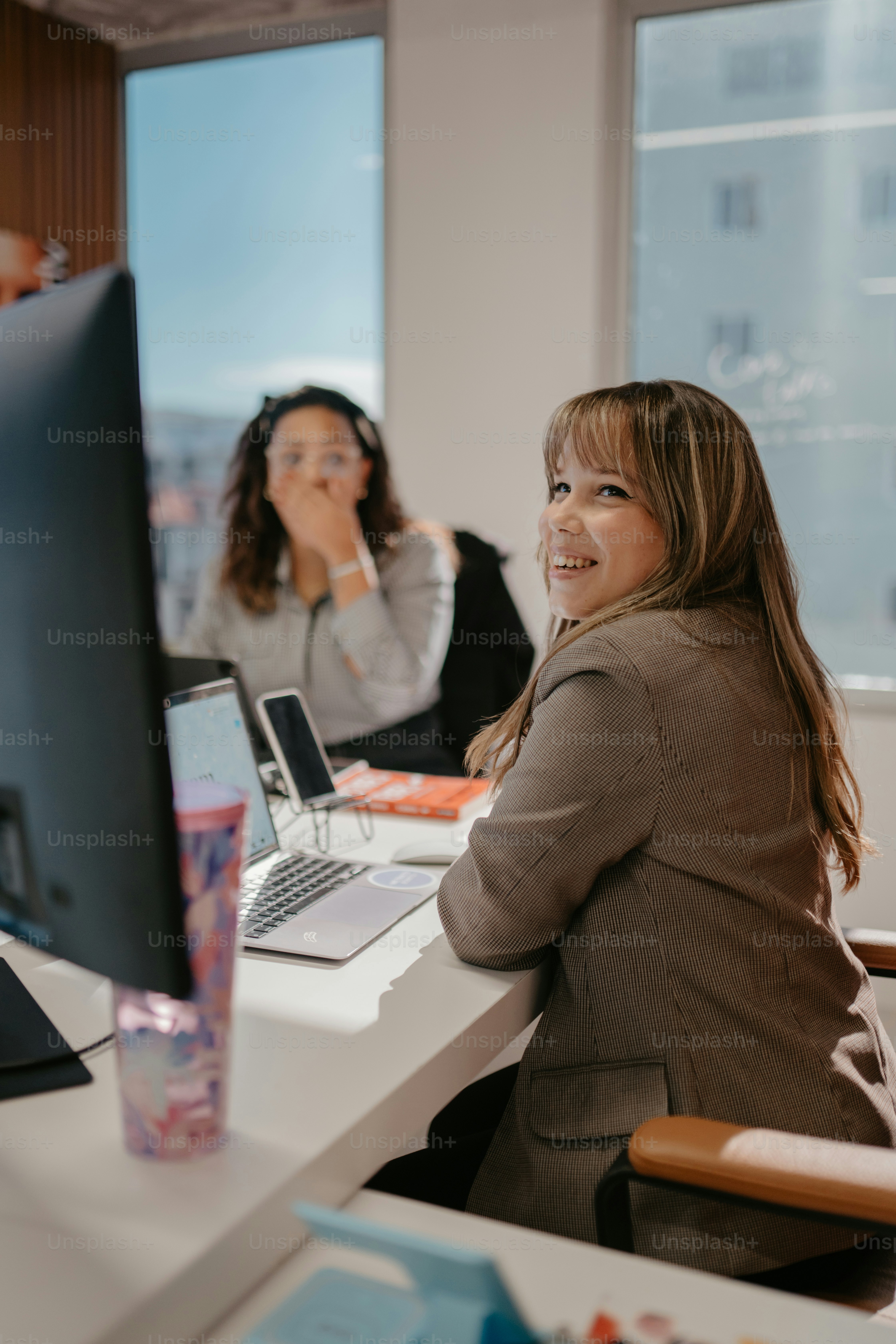 a woman sitting at a desk with a laptop computer