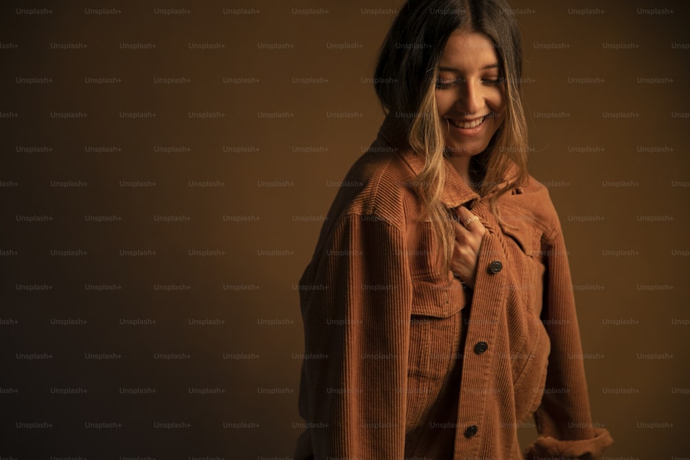 a woman smiling and wearing a brown jacket