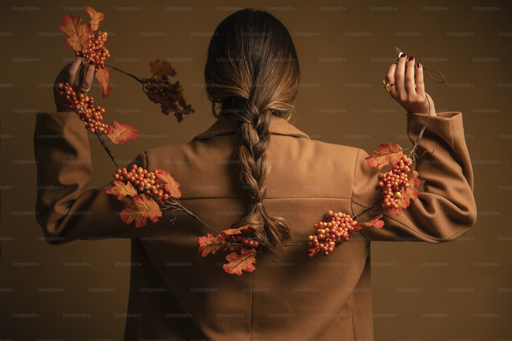 a woman in a brown coat holding a bunch of flowers