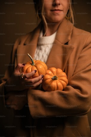 a woman is holding a bunch of pumpkins