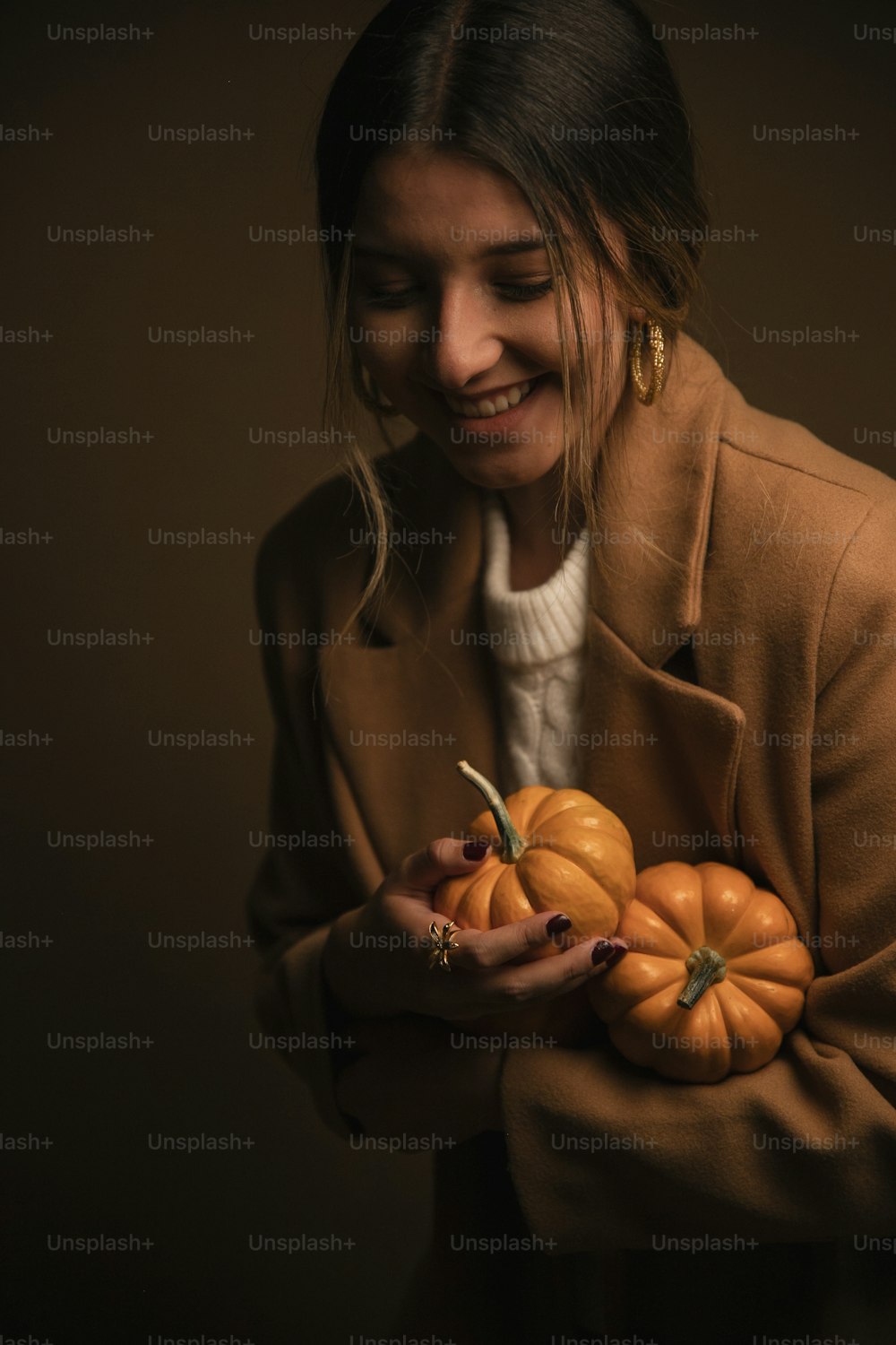 a woman holding a bunch of pumpkins in her hands