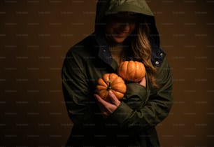 a man in a green jacket holding two pumpkins