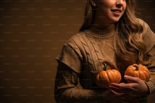 a woman holding two pumpkins in her hands