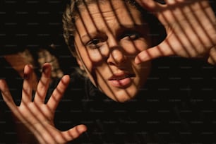 a woman holding her hands up behind a fence