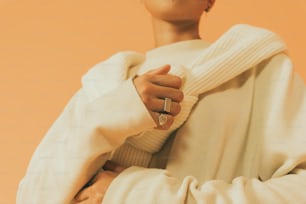 a woman wearing a white sweater and a ring