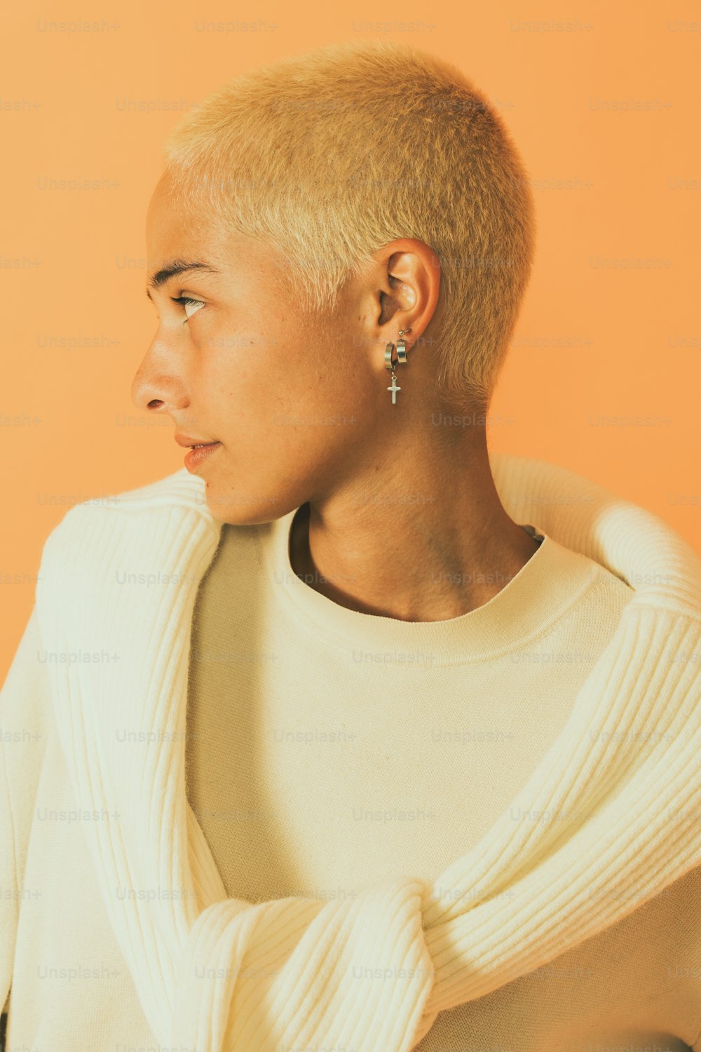 a woman with a shaved head wearing a sweater