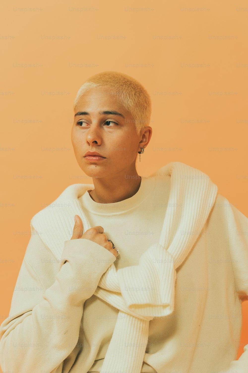 a man with a shaved head wearing a white sweater