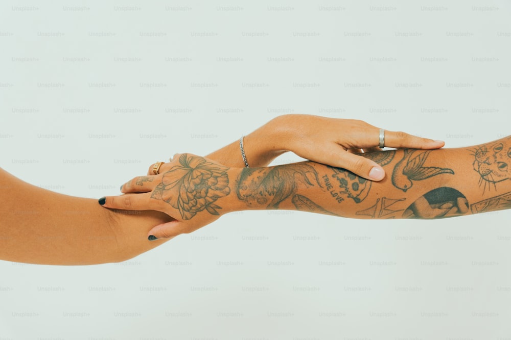 uma mulher com tatuagens no braço segurando o braço de outra mulher