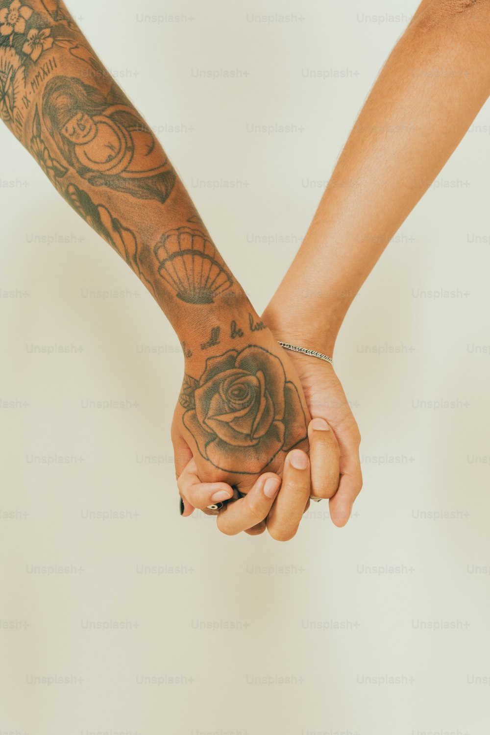 Deux personnes se tenant la main avec des tatouages sur les bras