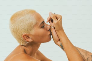 a woman with blonde hair and piercings kissing her nose