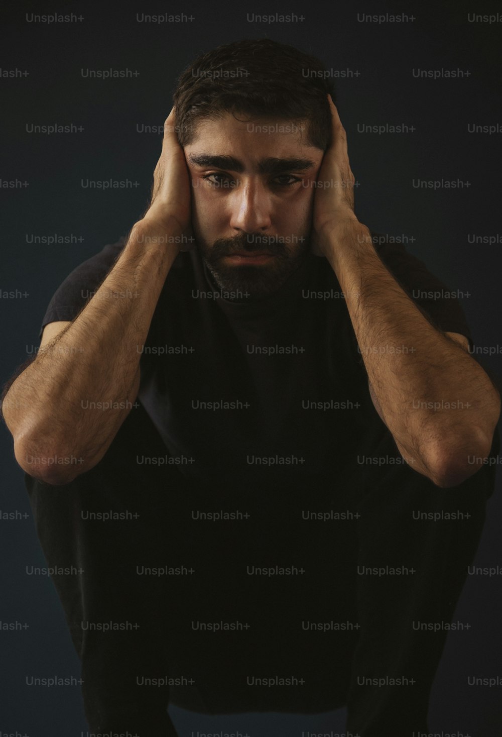 a man with a beard is holding his hands to his head