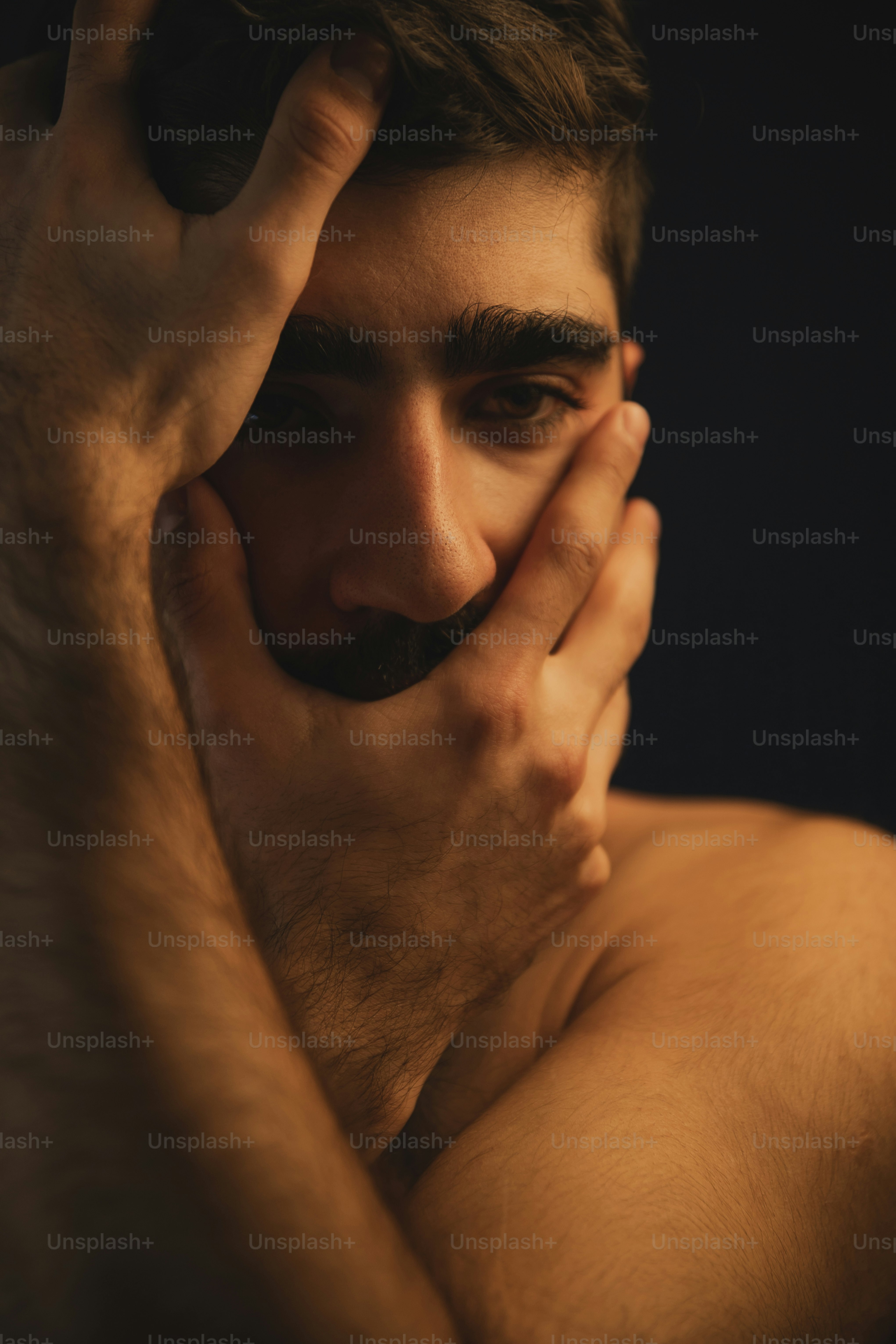 a shirtless man with a mustache covering his face
