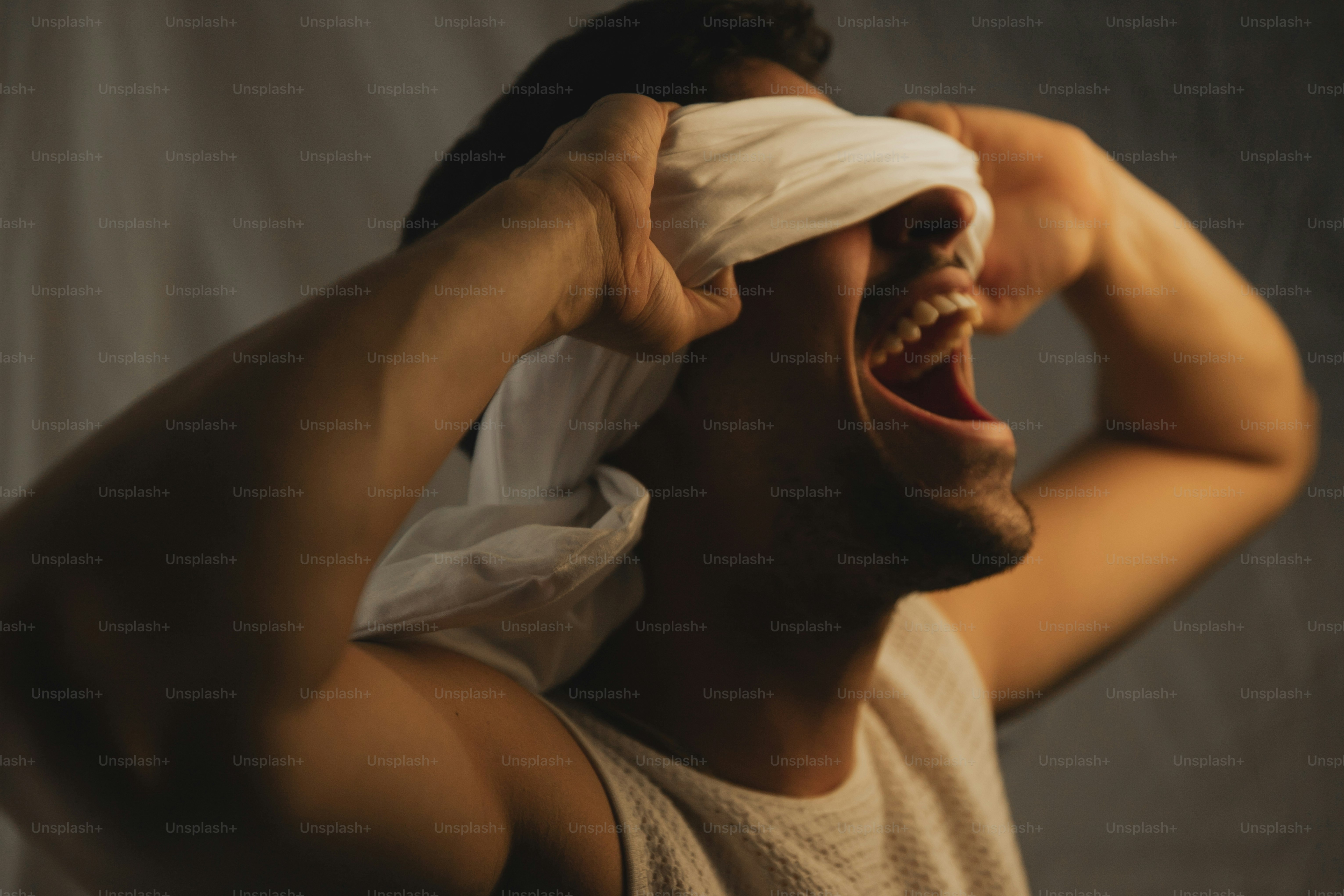 a man holding a white cloth over his eyes
