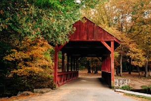 eine rote überdachte Brücke in einem Waldgebiet