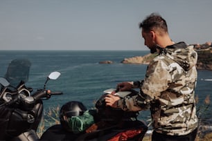 a man sitting on a motorcycle next to the ocean