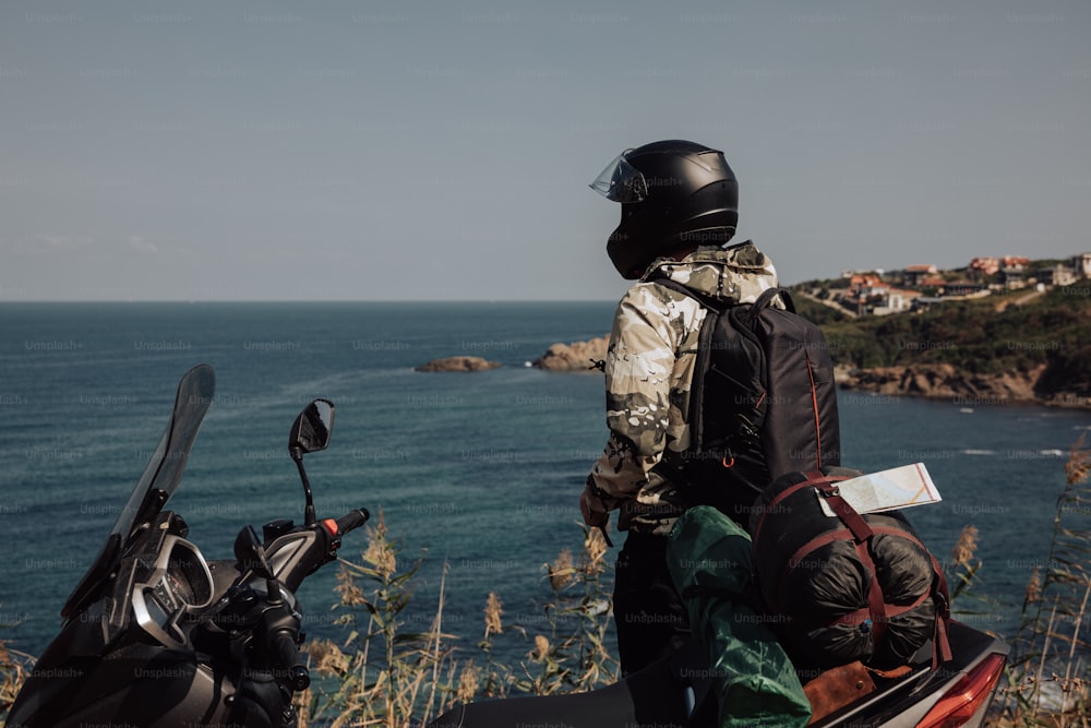 a person on a motorcycle looking out at the ocean