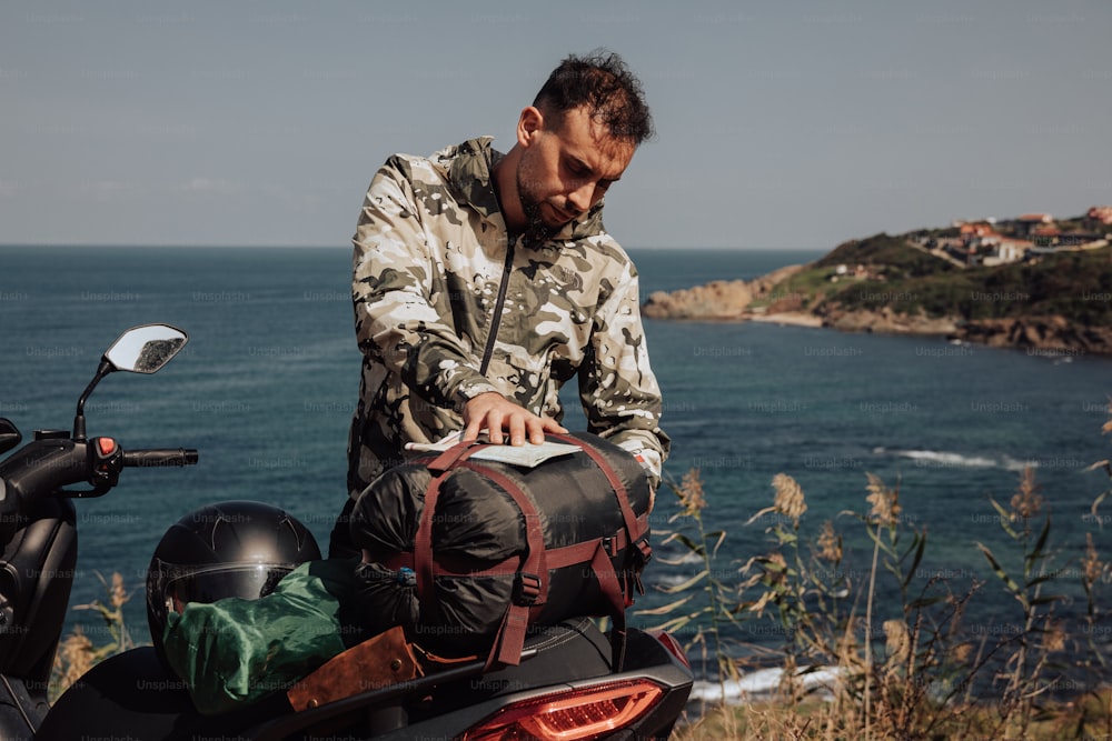 un uomo in piedi accanto a una motocicletta vicino all'oceano