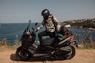 a man riding on the back of a motorcycle next to the ocean