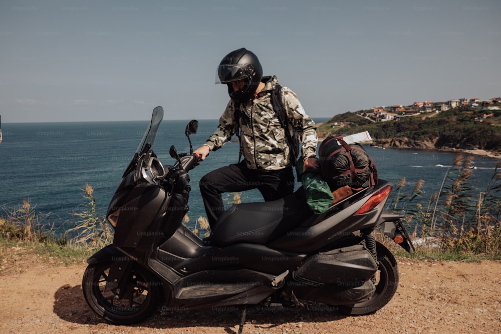 un uomo che cavalca sul retro di una motocicletta vicino all'oceano