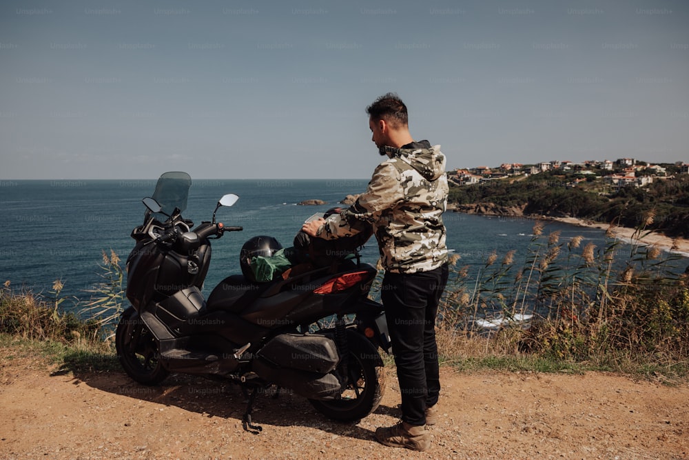 a man standing next to a motorcycle near the ocean