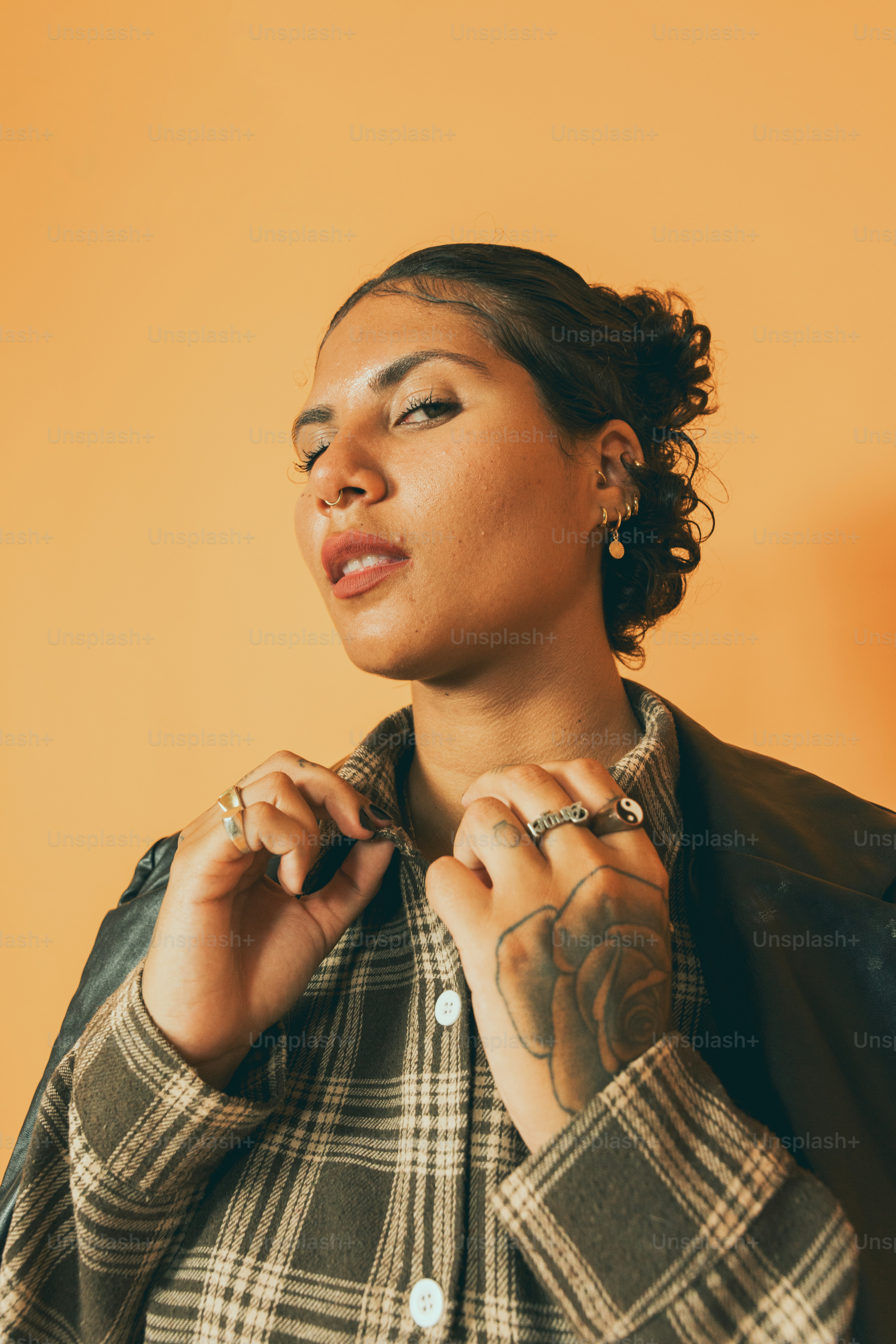 a woman wearing a plaid shirt and a leather jacket