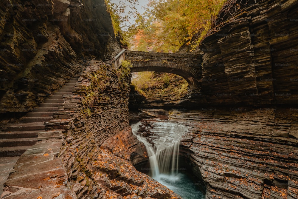 a river running through a rocky gorge next to a stone bridge