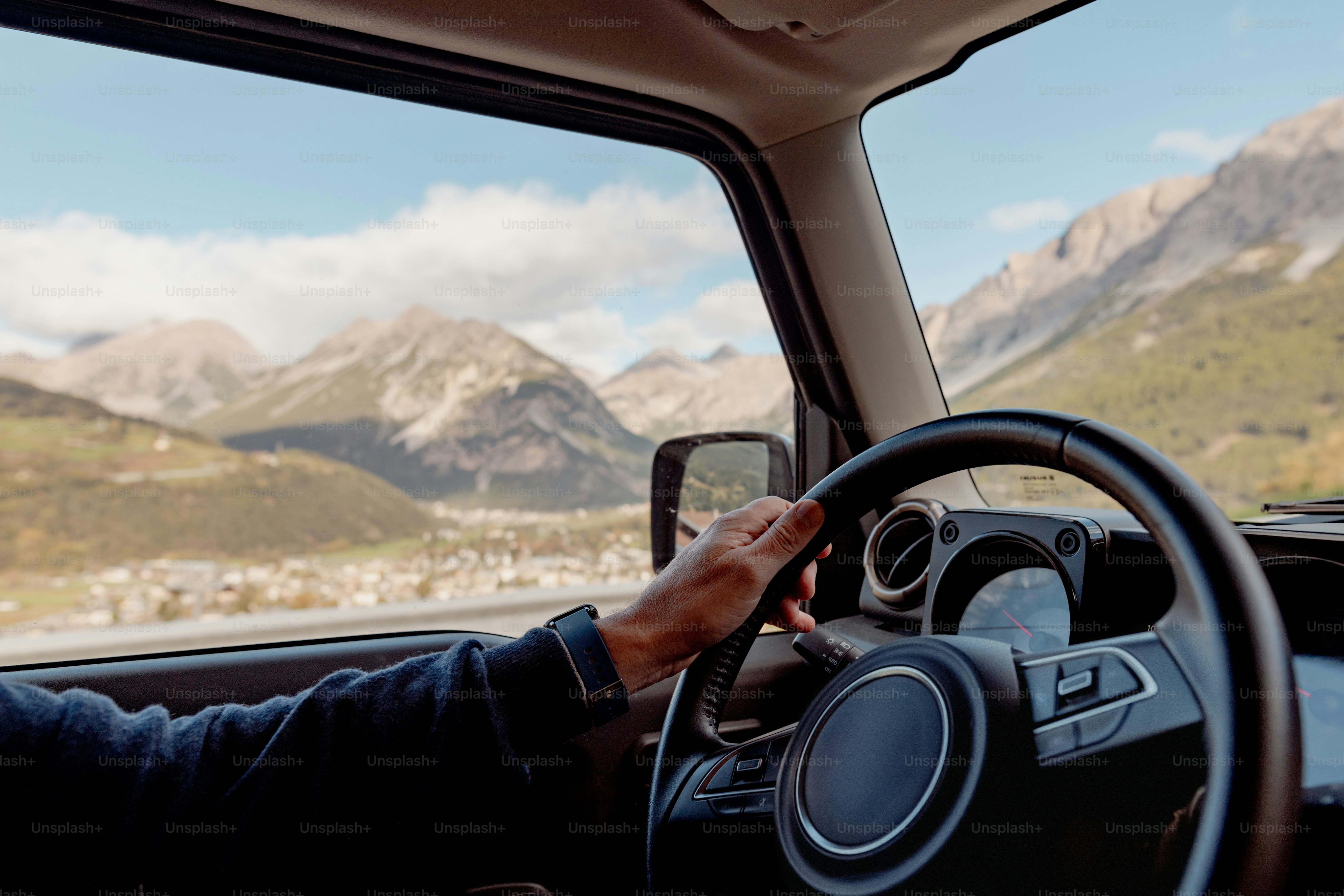 a person driving a car with mountains in the background