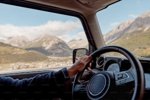 una persona conduciendo un coche con montañas de fondo