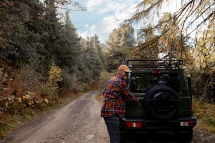 a man standing next to a jeep on a dirt road