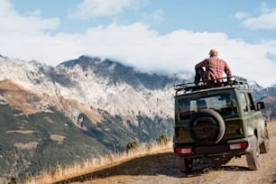 two people sitting on top of a vehicle on a dirt road