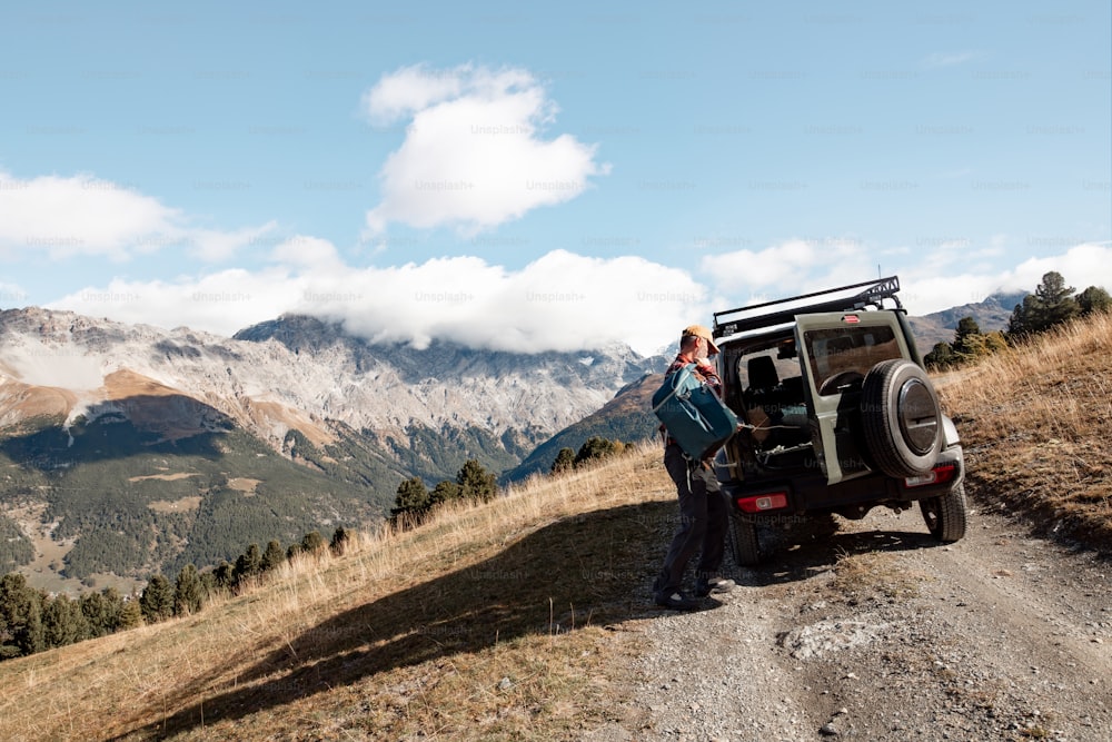 a woman standing next to a jeep on a dirt road