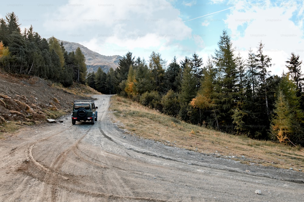 Ein Jeep fährt eine unbefestigte Straße in der Nähe eines Waldes entlang
