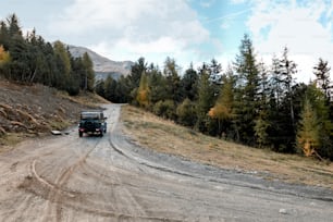 a jeep driving down a dirt road near a forest