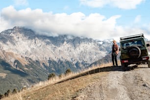 a man standing next to a jeep on a dirt road