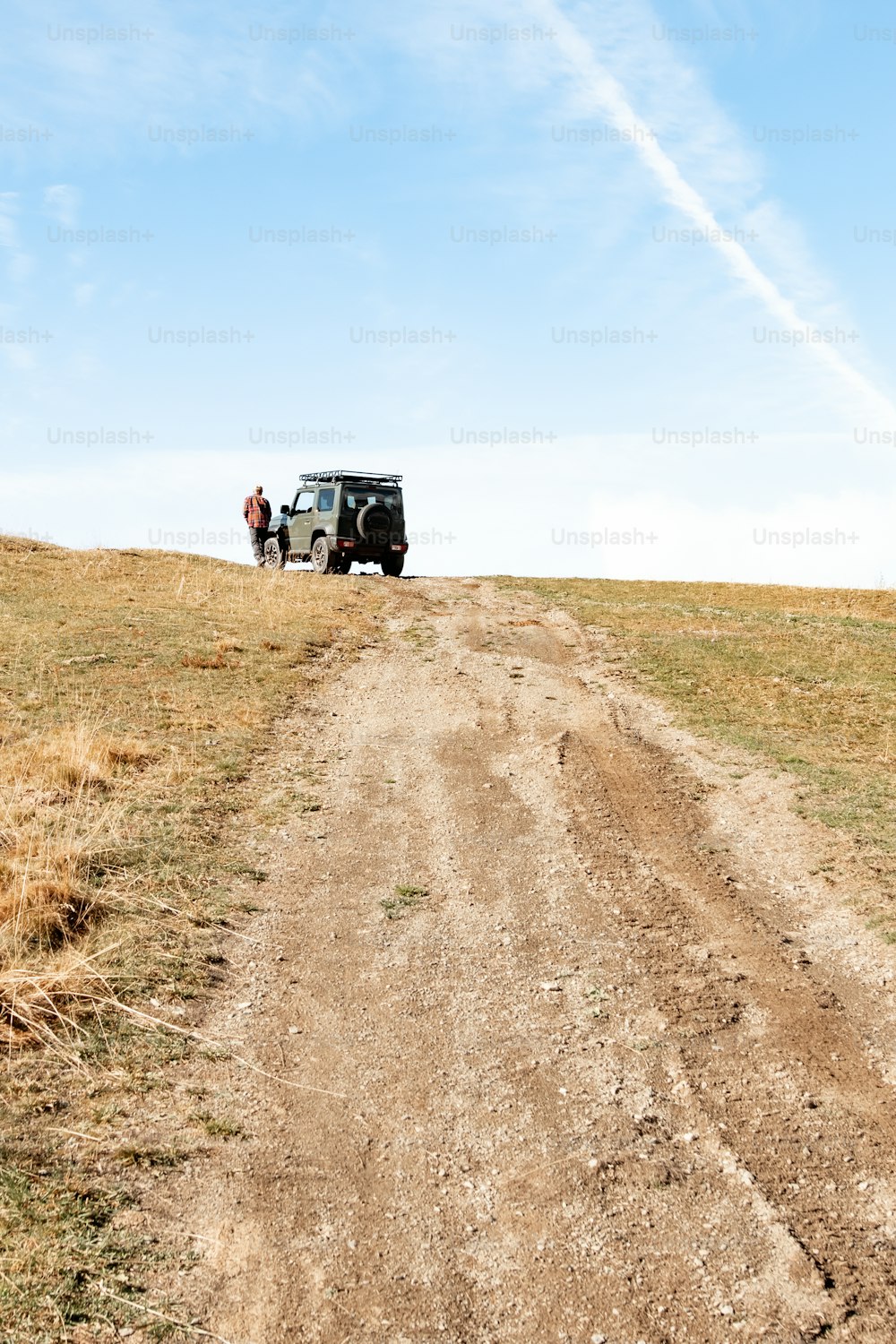 a jeep driving down a dirt road in the middle of a field