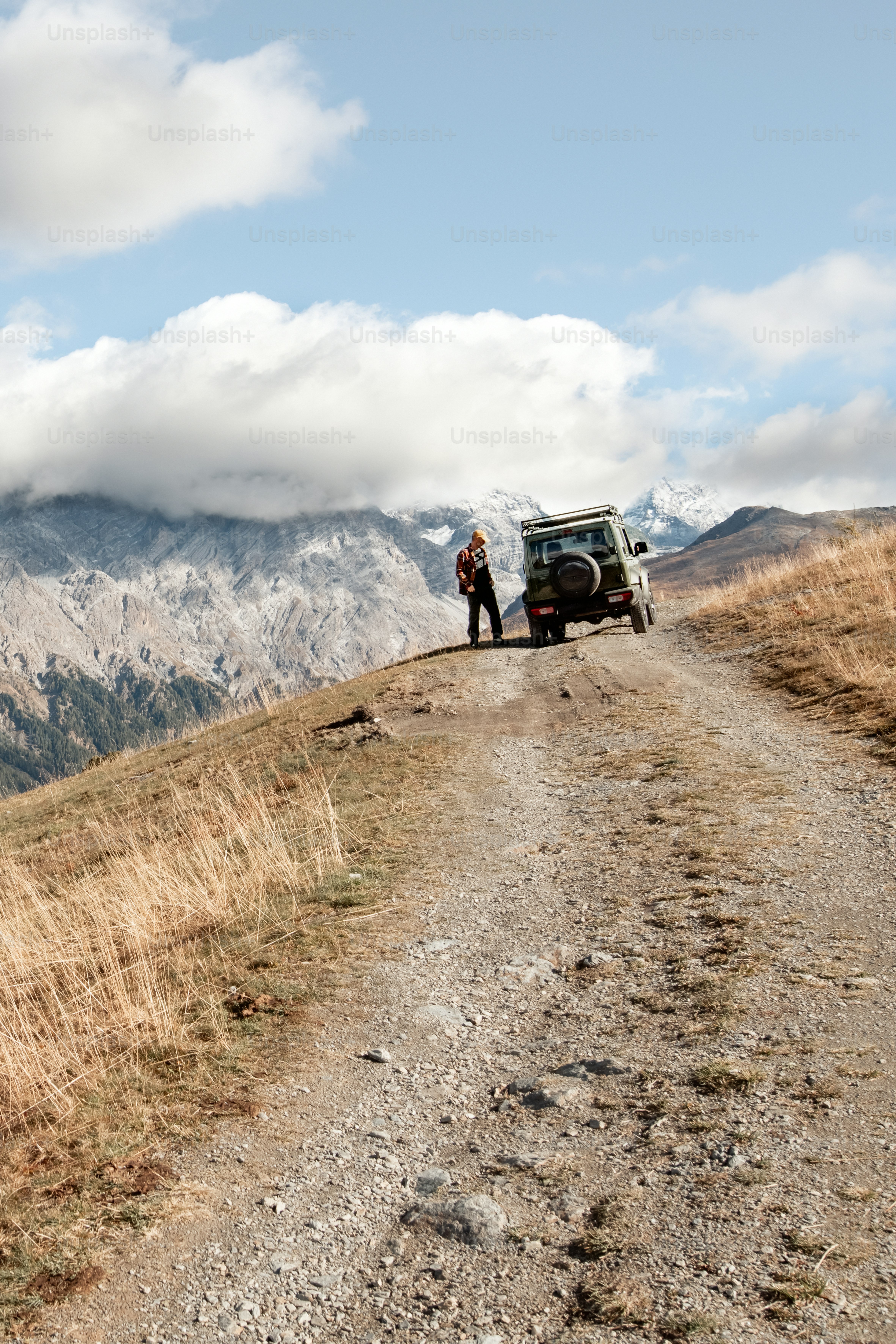 a man standing next to a truck on a dirt road