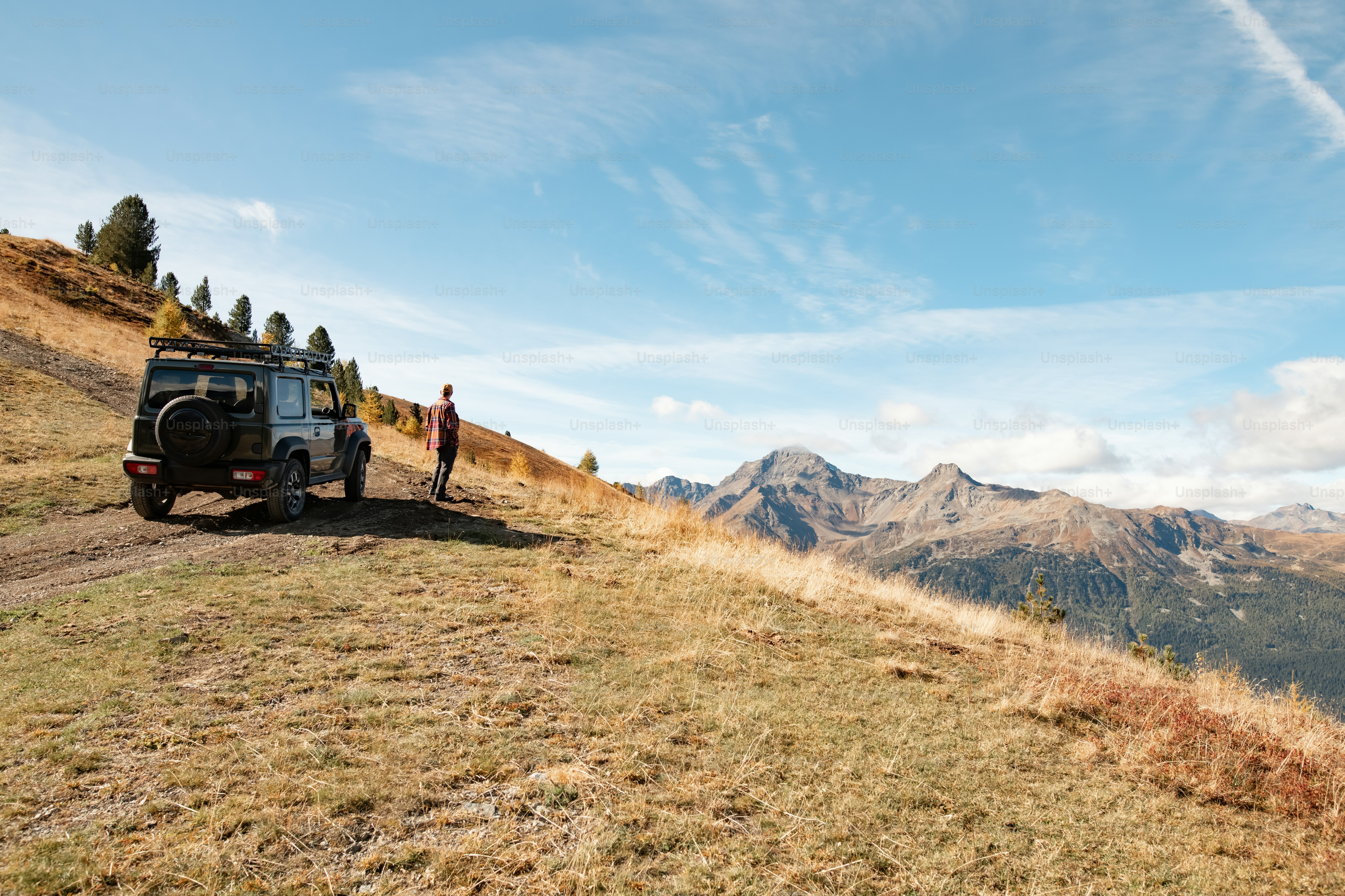 a man standing on top of a hill next to a vehicle