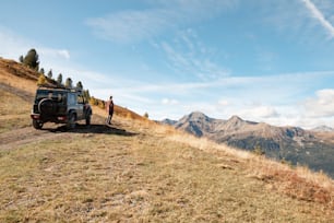 un homme debout au sommet d’une colline à côté d’un véhicule