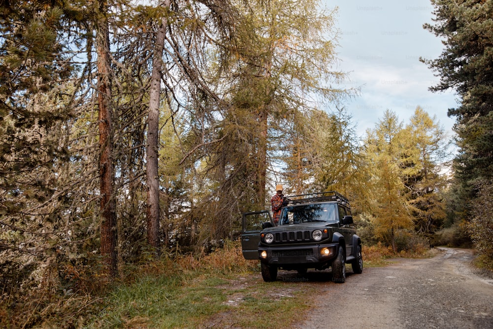 a jeep driving down a dirt road in the woods