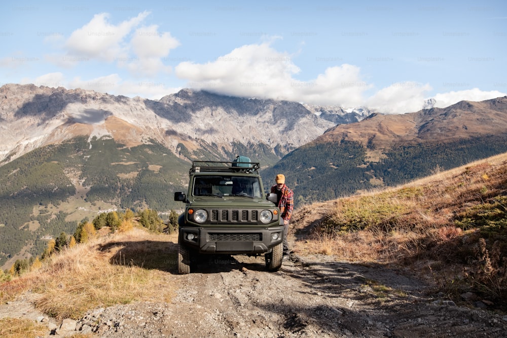 a man standing next to a jeep on a dirt road